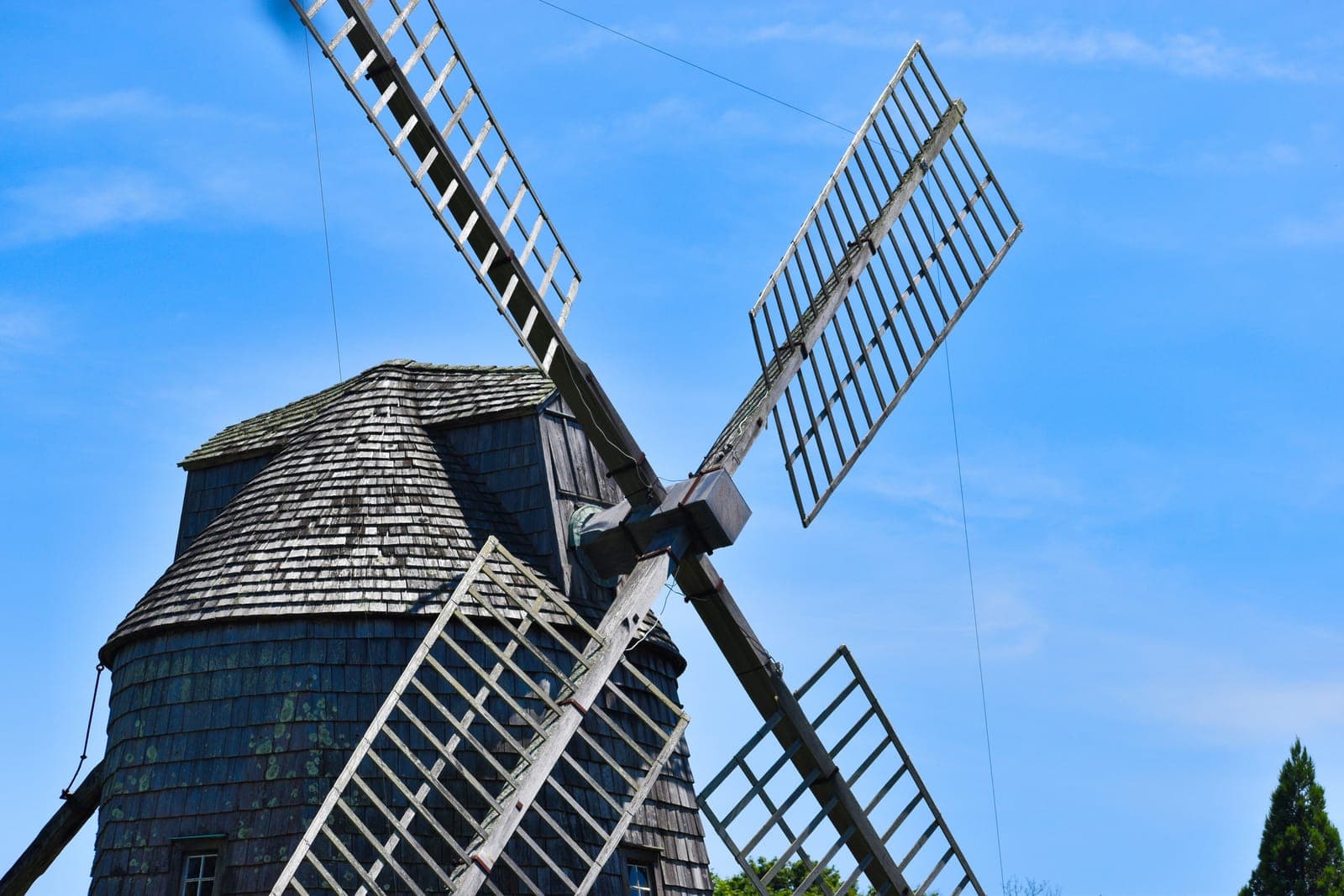 The historic wooden grist windmill of Water Mill, NY against a bright blue sky — the namesake windmill of the hamlet